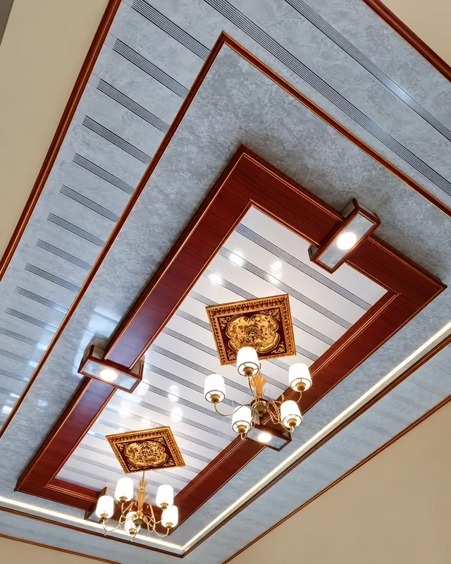 Plafon PVC bertingkat dengan panel motif marmer abu-abu, bingkai motif kayu dan dua lampu gantung